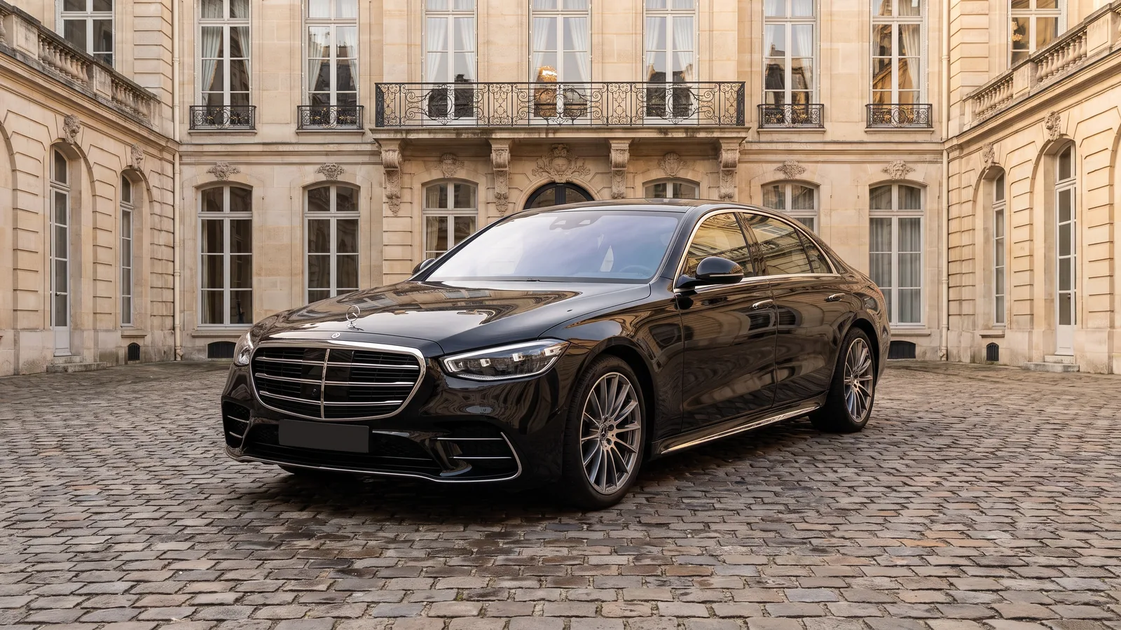 Mercedes-Benz Classe S noire, trois quarts avant, dans la cour pavée d'un hôtel particulier parisien